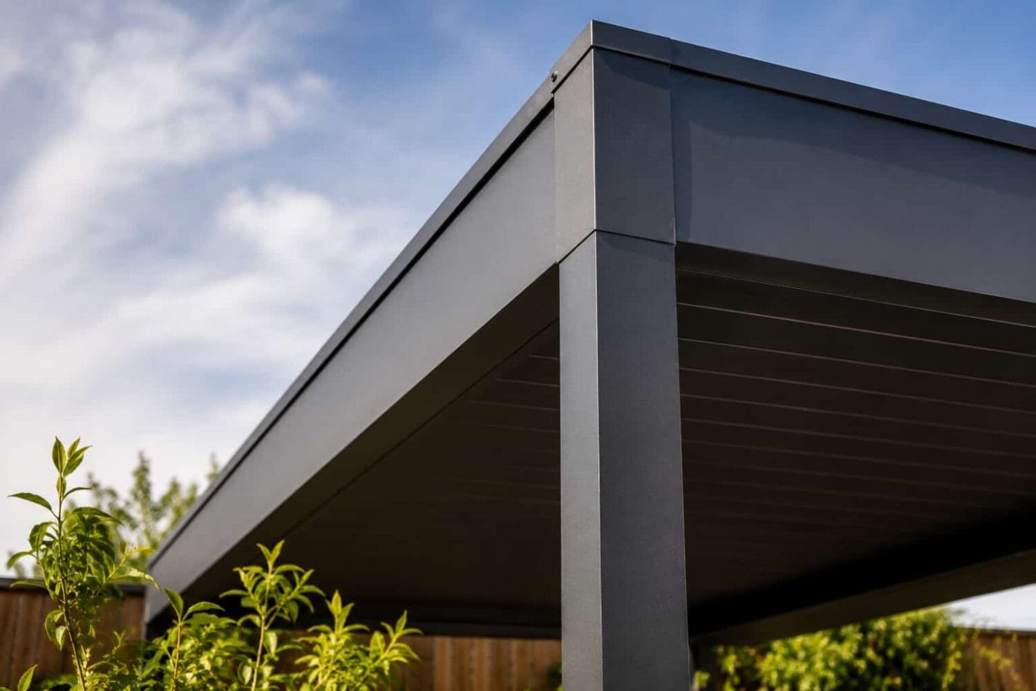 Close up of a powder coated aluminum hardtop gazebo frame against a blue sky showing solid construction and clean modern lines.