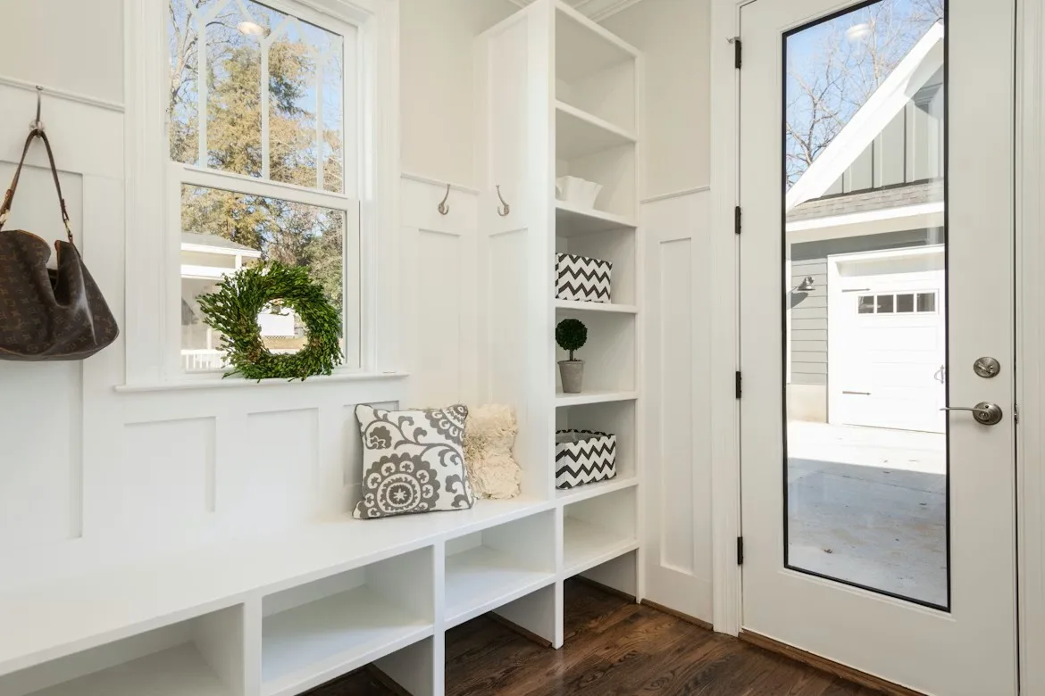 Home Organization Ideas: Bright white mudroom with built-in bench, cubbies, hooks, and shelving with chevron storage boxes.