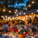 4th of July party table decorated with red, white, and blue flowers under string lights at twilight — save this for your next backyard celebration!
