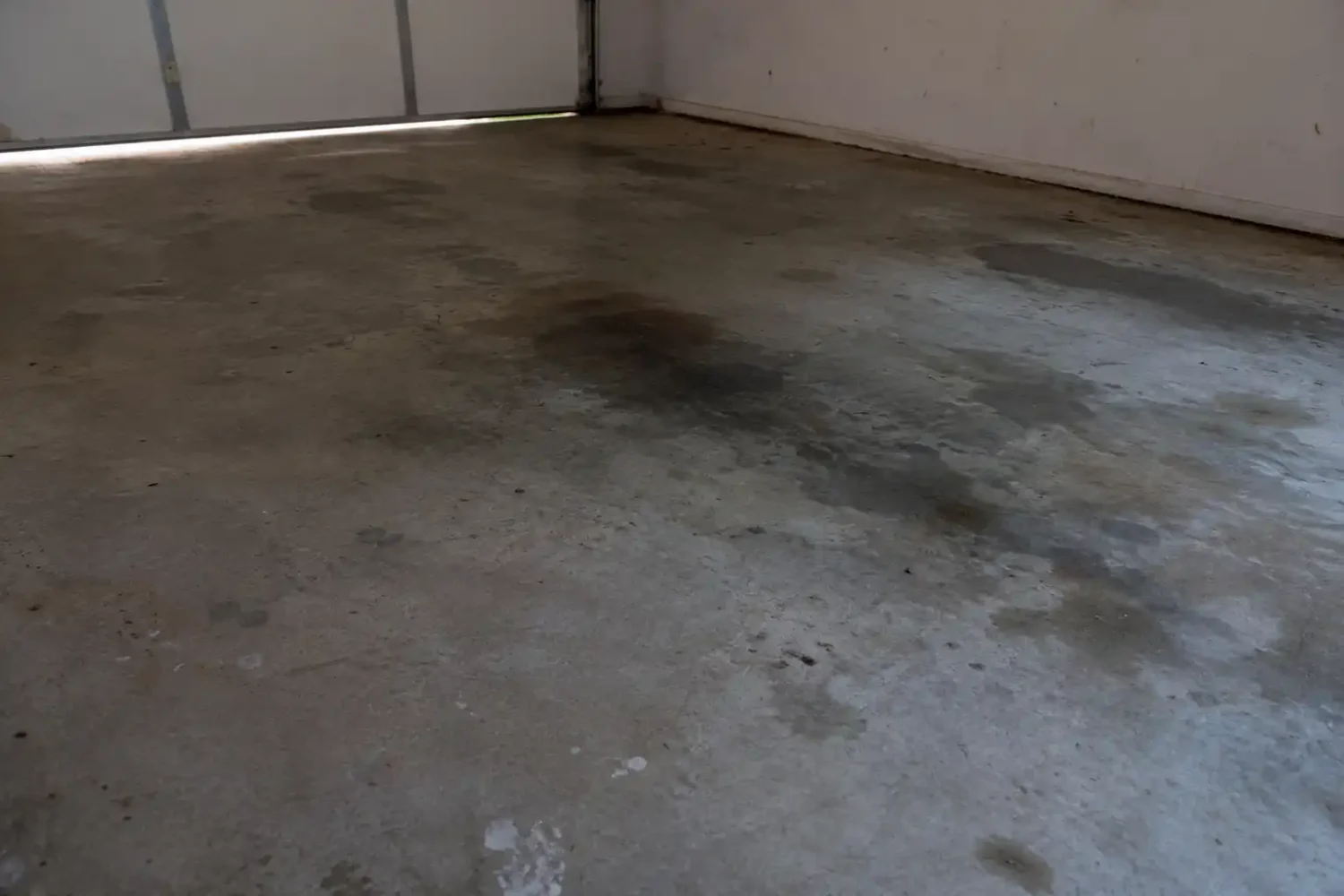 Bare concrete garage floor with oil stains before rubber gym flooring installation.