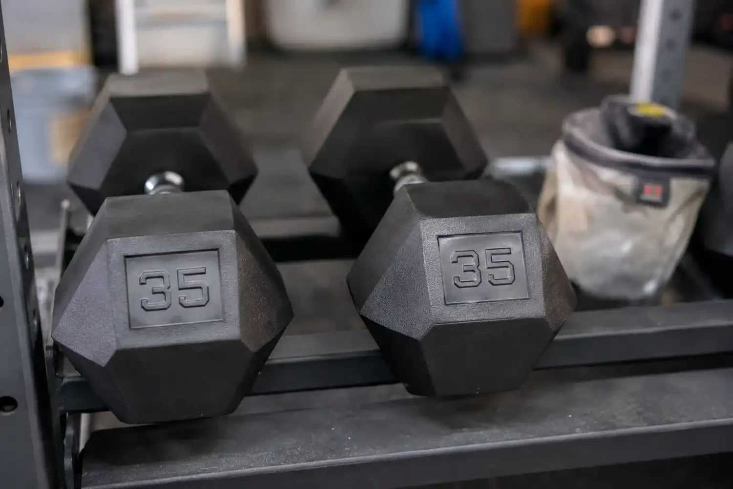 Close up of hex dumbbells with clearly legible weight numbers under angled lighting.