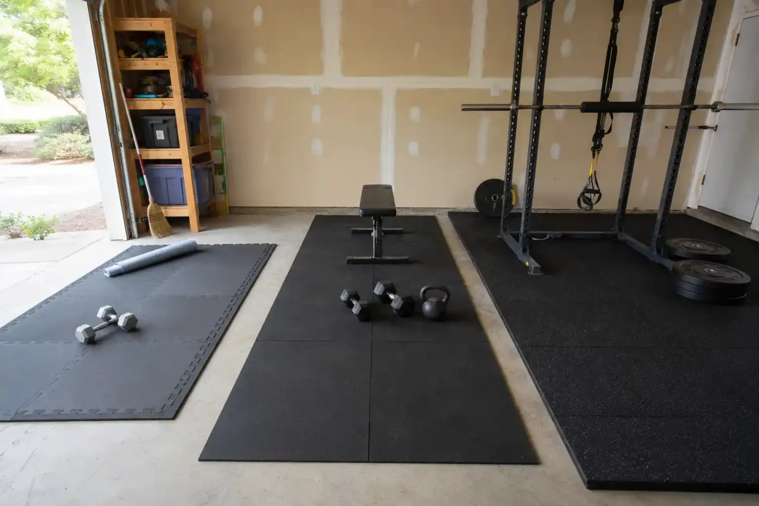 Three garage gym flooring options shown side by side, including interlocking mats, rubber tiles, and thick rubber flooring with weights and a power rack.