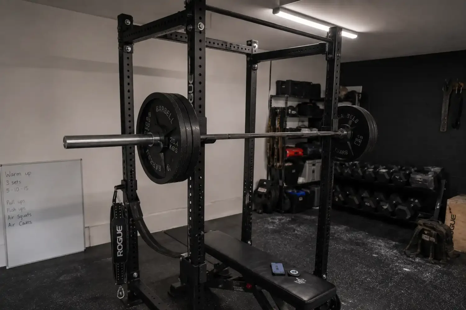 Garage gym lighting creating shadows on equipment despite overhead light fixture.