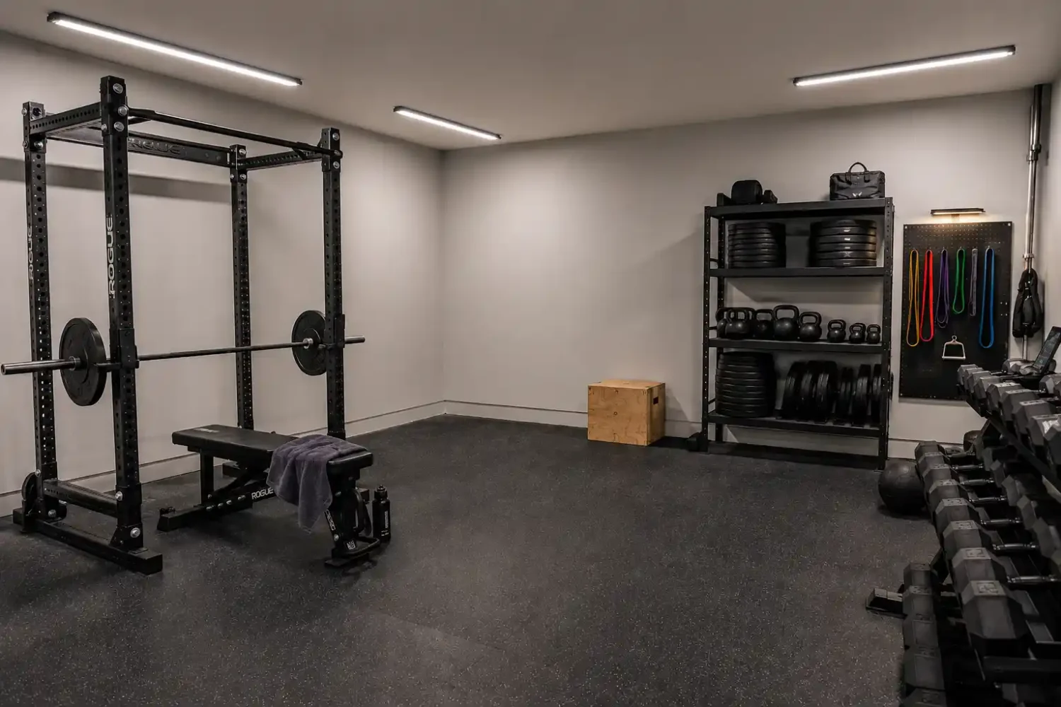 Garage gym with multiple ceiling light fixtures providing even coverage across the rack, storage, and open floor