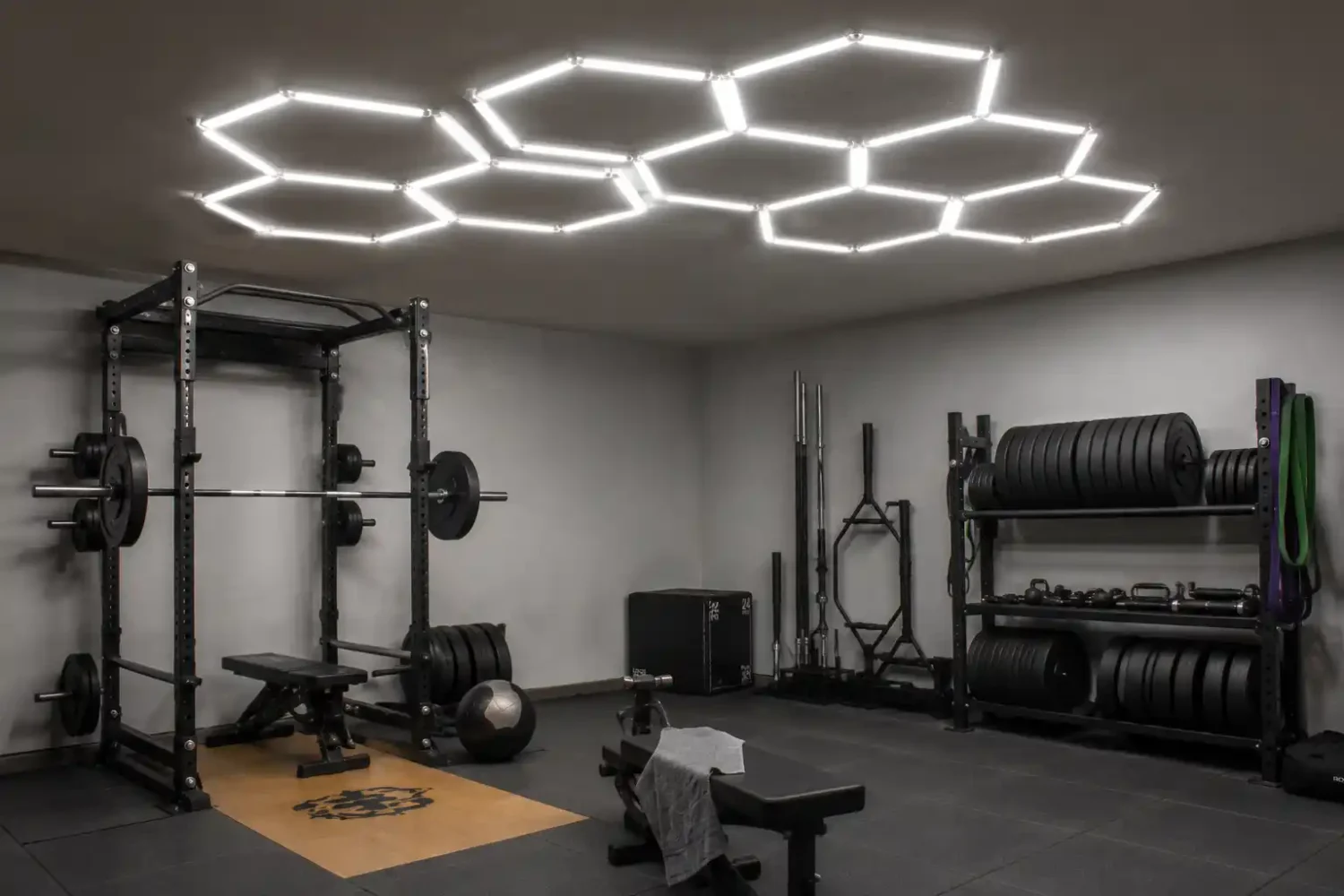 Hexagon shaped LED ceiling lights mounted above a garage gym power rack and storage area.