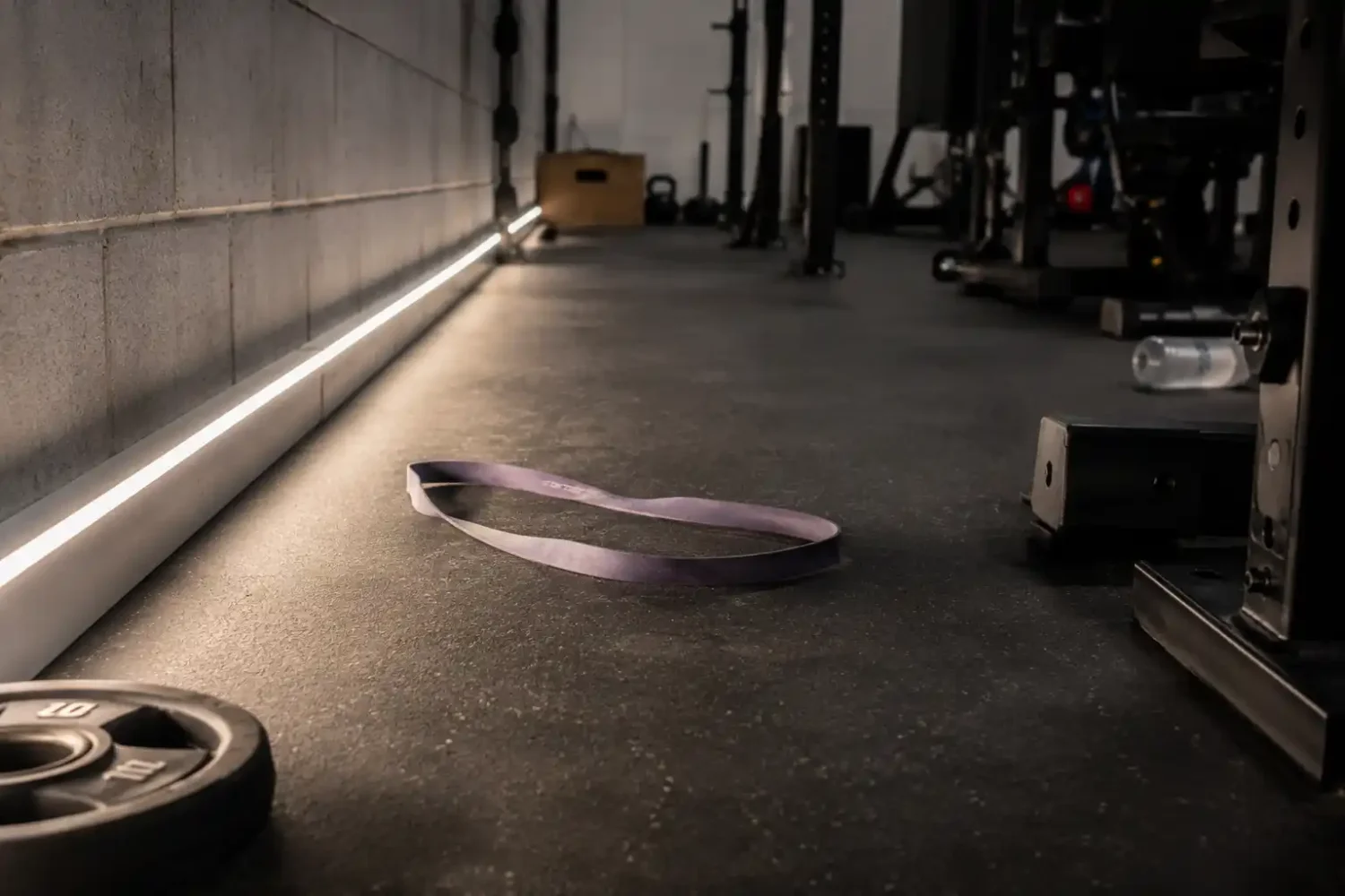 Resistance band visible on garage floor under a low mounted LED strip light along the wall.