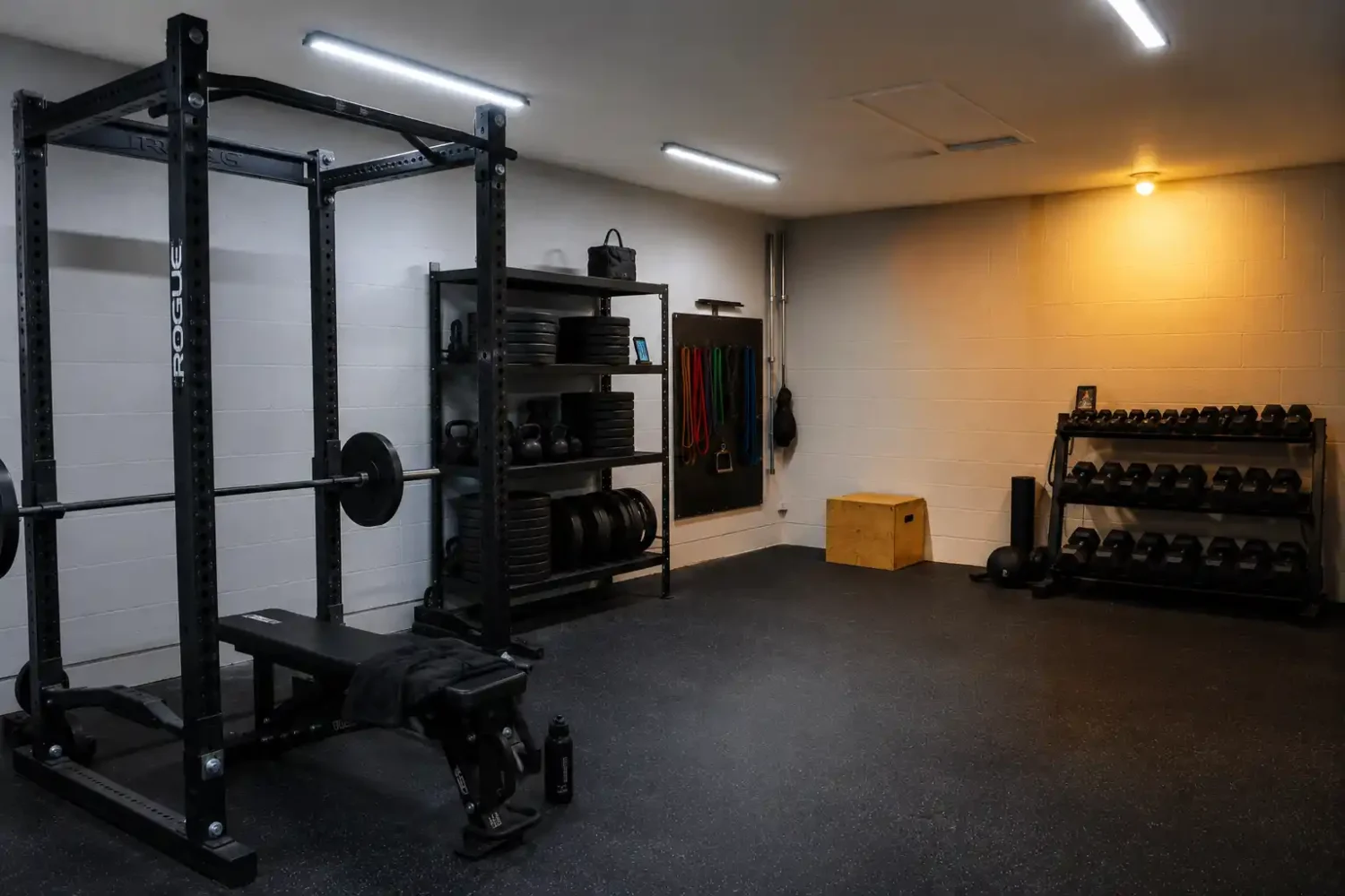 Garage gym corner with mismatched warm yellow lighting next to properly lit white LED area.